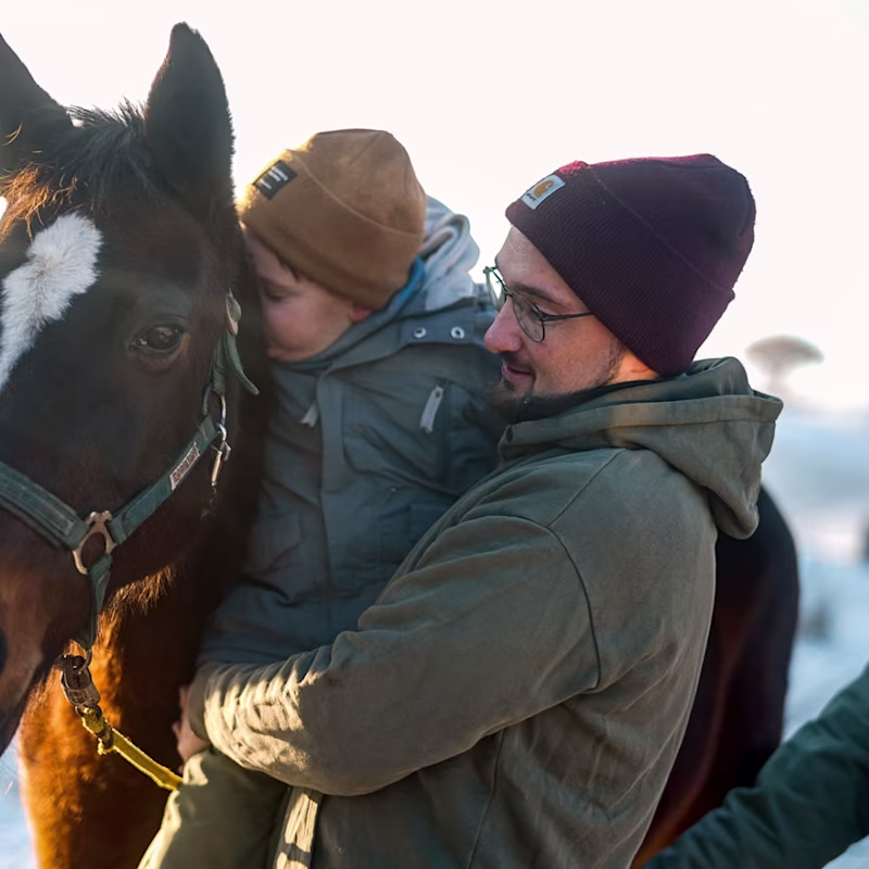Cerebral palsy patient petting a horse together with his father
