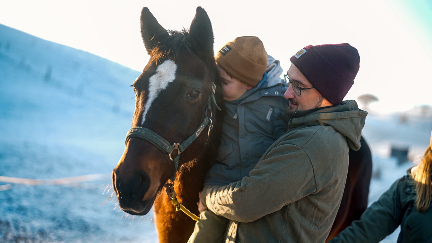Cerebral palsy patient petting a horse together with his father 