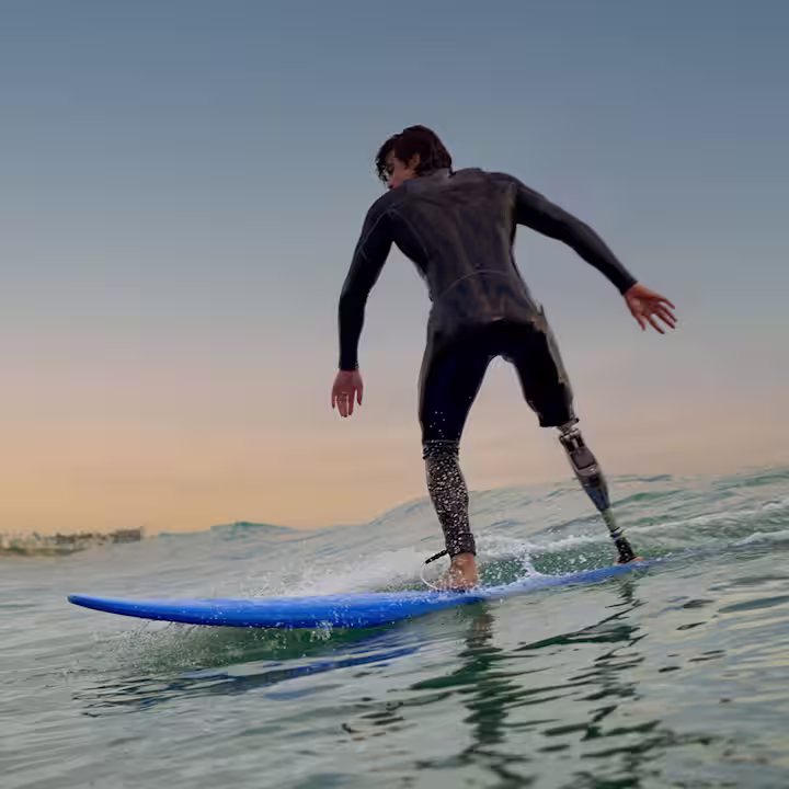A Genium X4 microprocessor knee (MPK) user is surfing during sunset