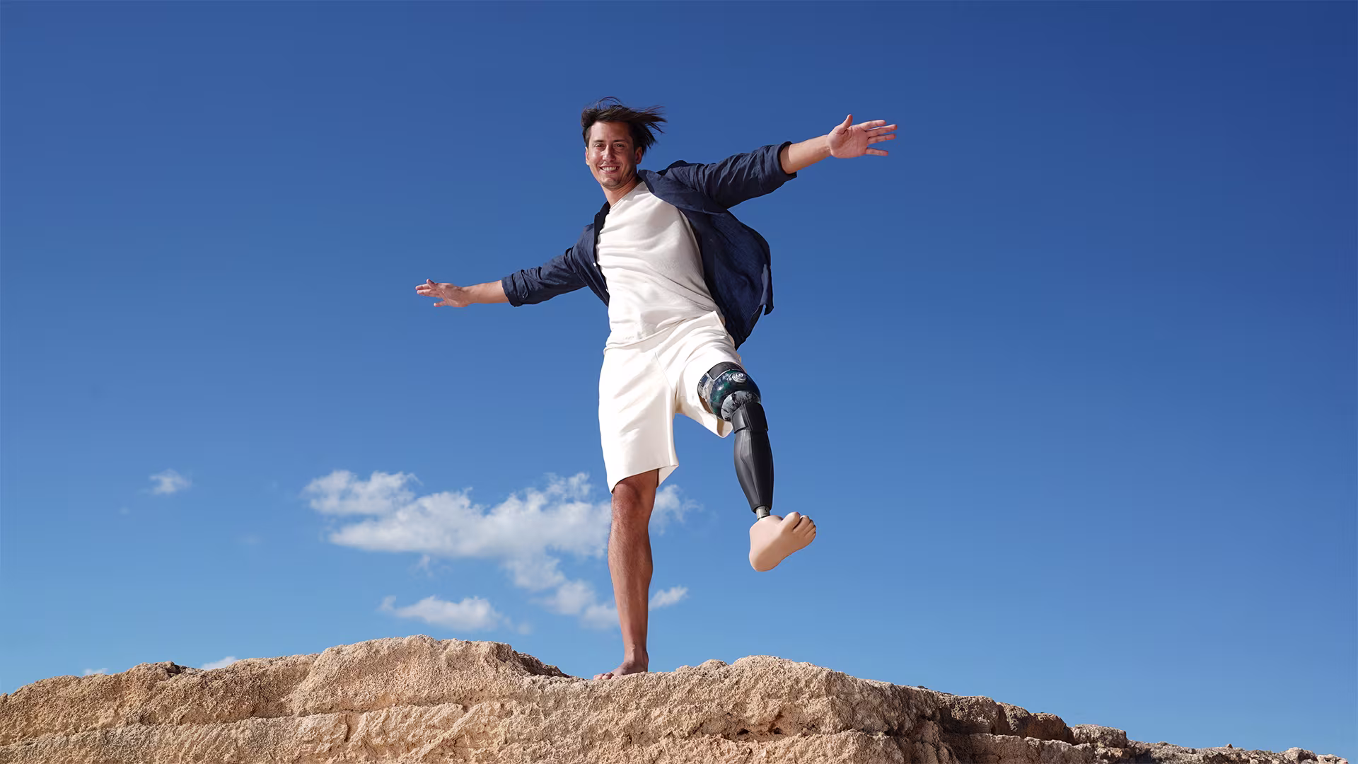 Alessandro Ossola with his Evanto prosthetic foot and Genium X3 microprocessor knee standing on a rock.