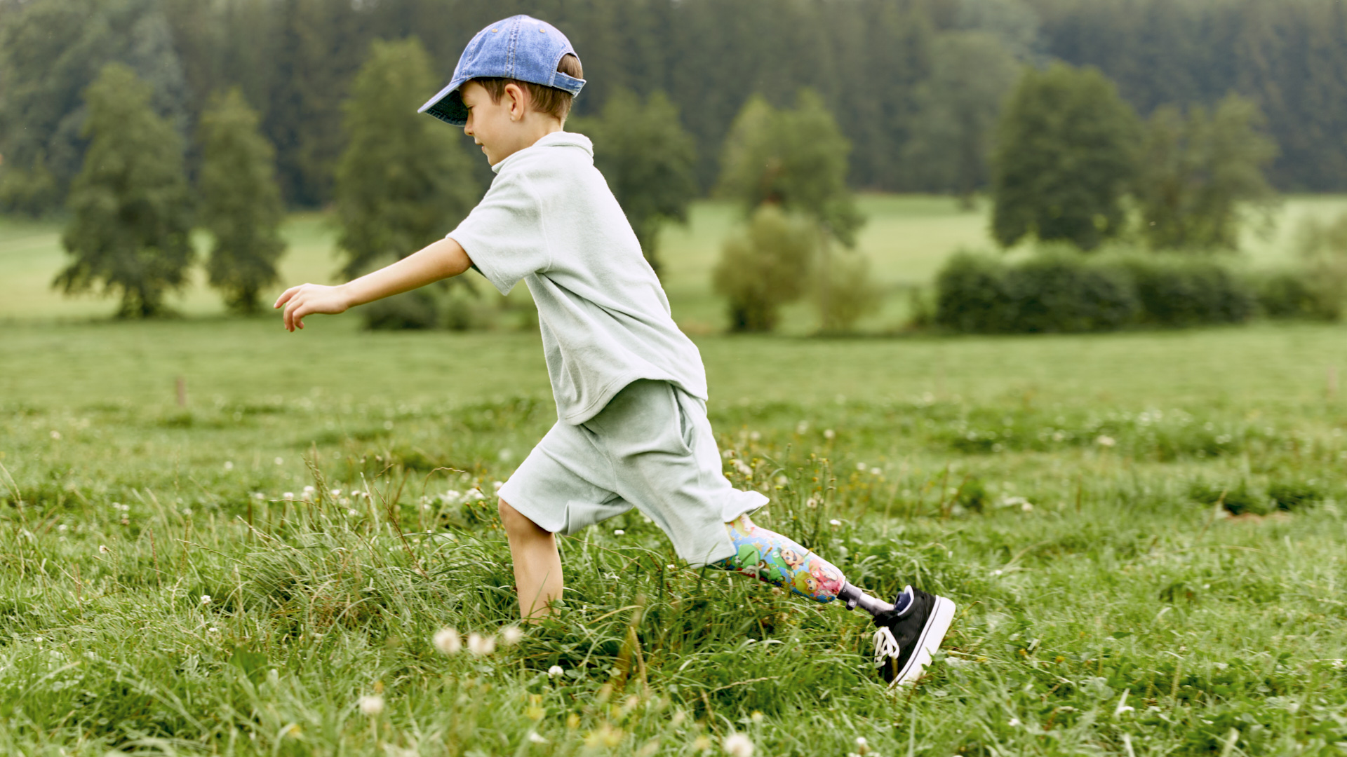Auf dem Bild sieht man einen Jungen, der lächelnd über den Rasen läuft und die Beinprothesen Maverick junior & movido von Ottobock trägt. 