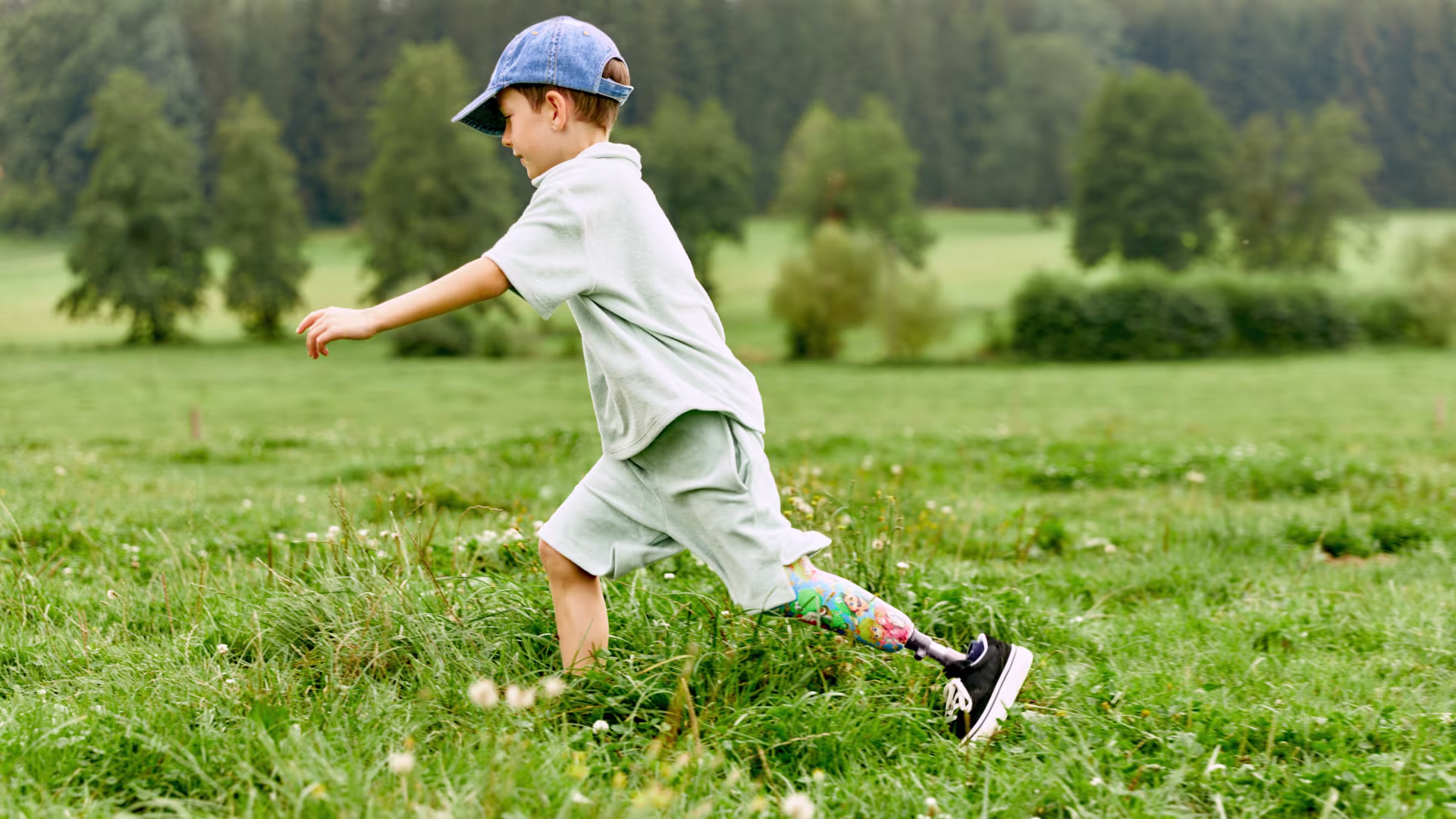 Auf dem Bild sieht man einen Jungen, der lächelnd über den Rasen läuft und die Beinprothesen Maverick junior & movido von Ottobock trägt. 