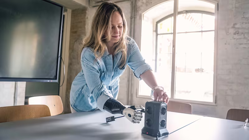 Eine Armprothesenträgerin benutzt eine Steckdose im Büro. Sie trägt die bebionic Hand von Ottobock.
