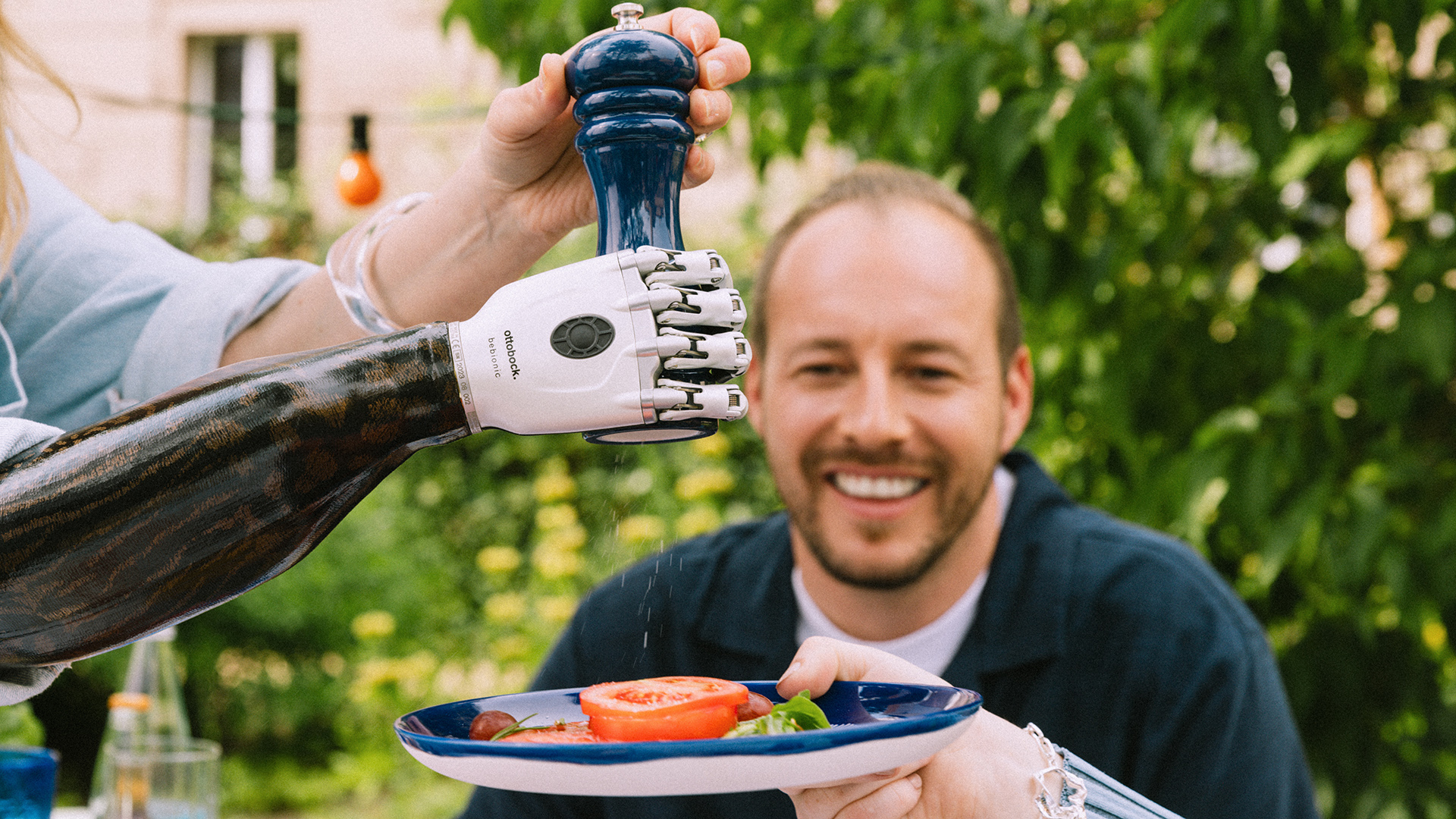 Eine Prothesenträgerin benutzt ihre bebionic Prothesenhand um mit Hilfe eines Salzstreuers einen Salat zu salzen.