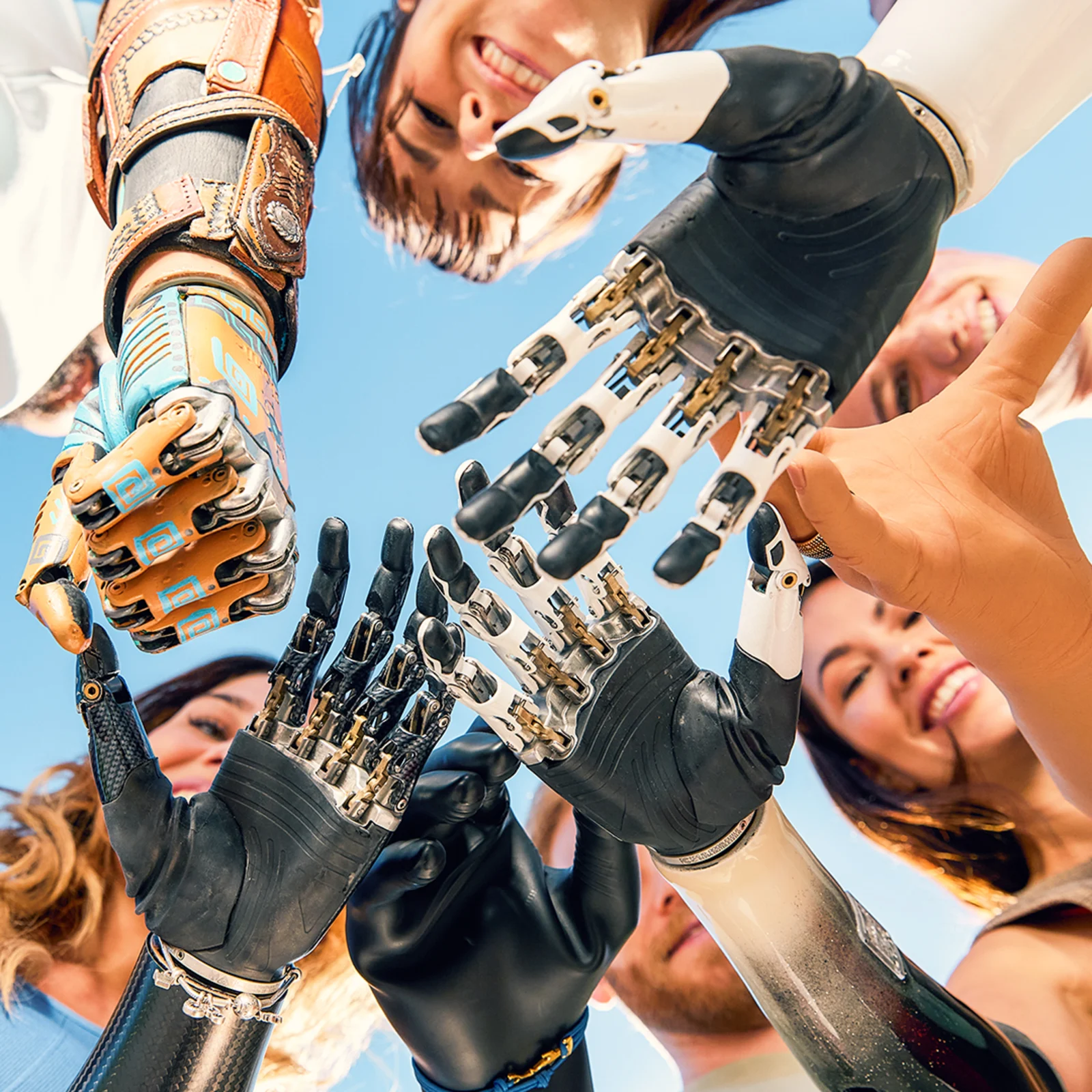 Various Ottobock prosthetic hand users huddle in a circle and stretch their hands in the center