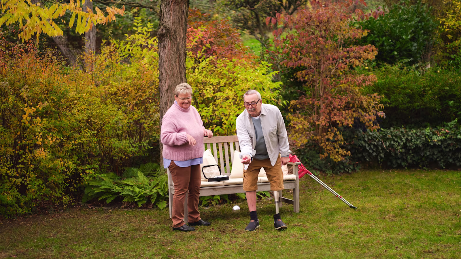 Мужчина пожилого возраста на протезе бедра играет в бочче в саду.