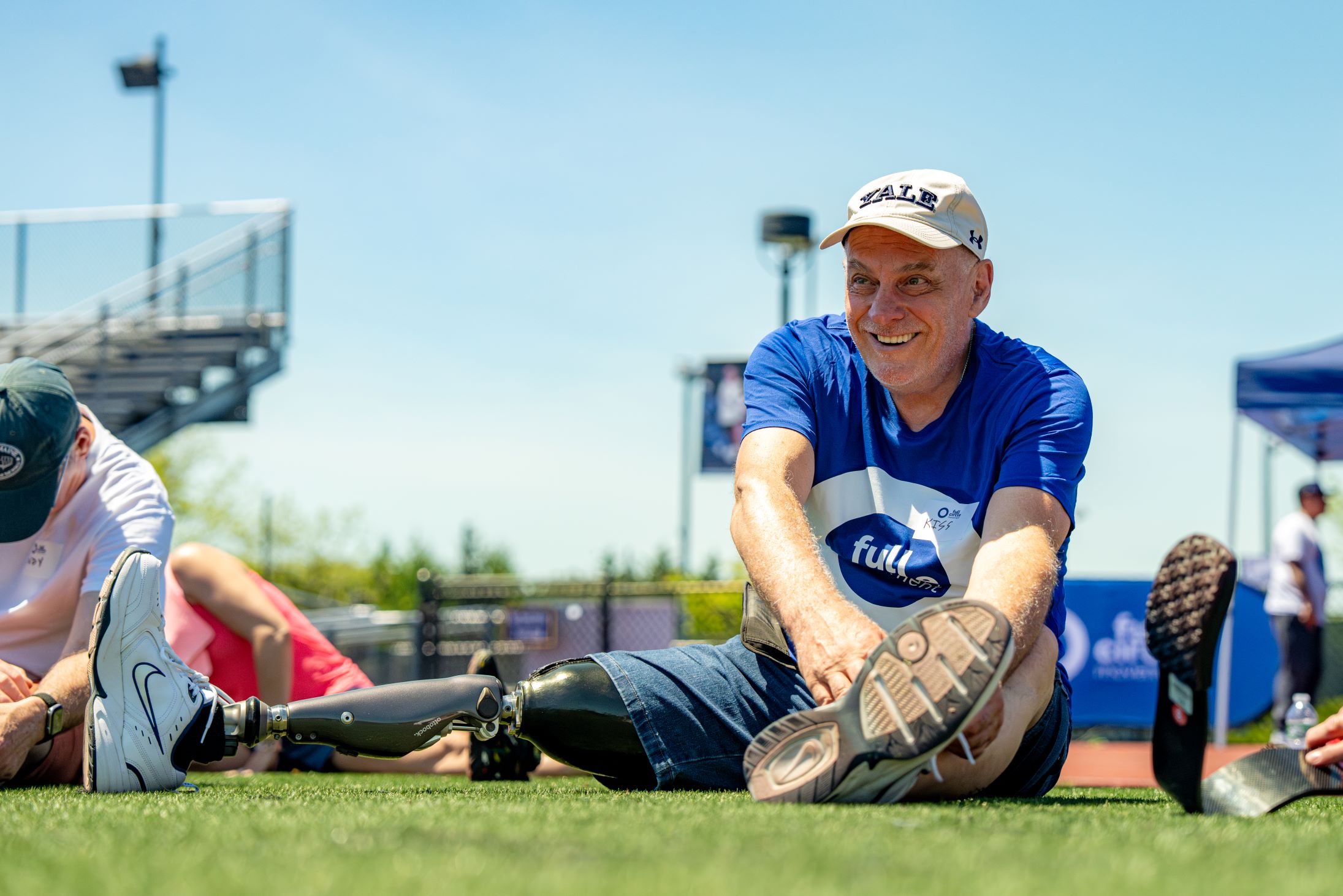 Lower limb amputated man smiles as he stretches before an adaptive sports event