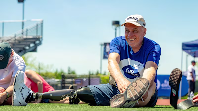 Lower limb amputated man smiles as he stretches before an adaptive sports event