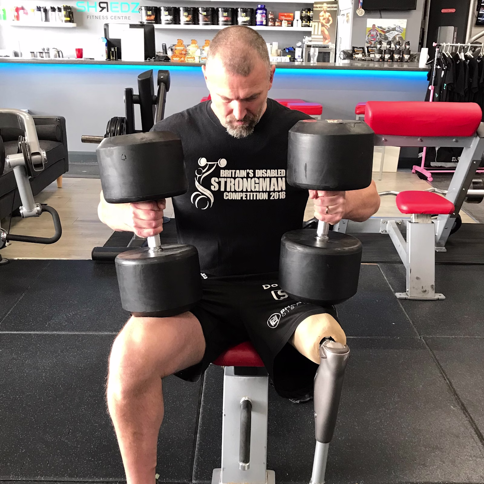 C-Leg Microprocessor Knee user Darren sitting on a exercise bench holding a dumbbell in each hand.