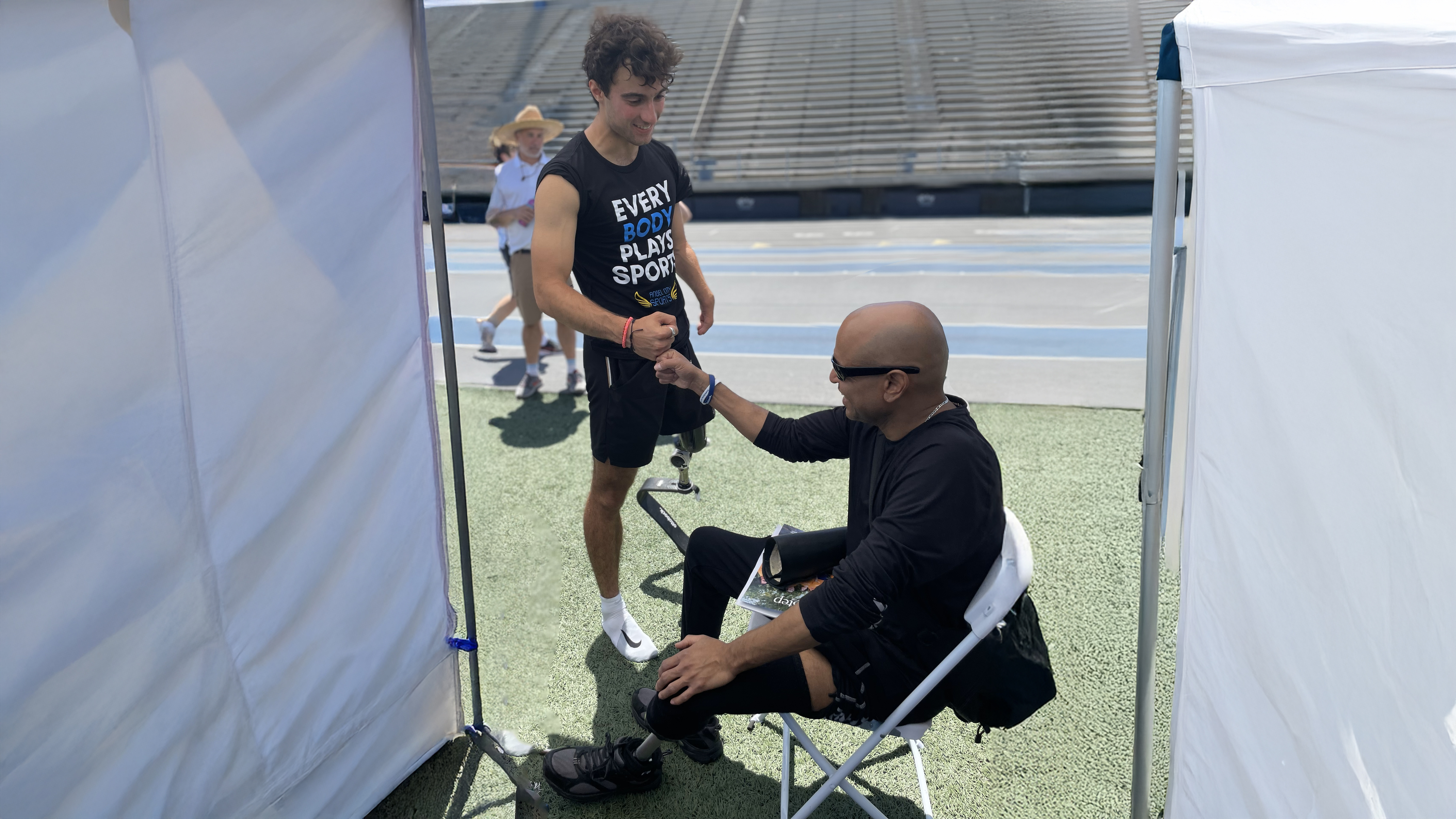 Ambassador and Paralympian Ezra Frech fist bumping with an attendee at the Ottobock Running Clinic