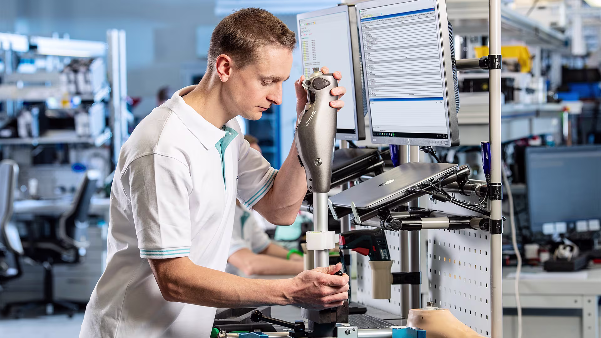 Ottobock technician using handheld device to inspect components in digital lab environment.