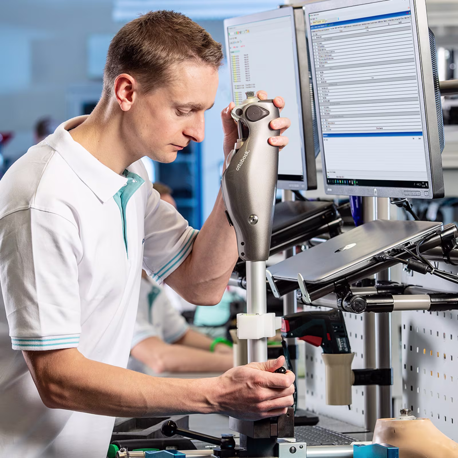 Ottobock technician using handheld device to inspect components in digital lab environment.