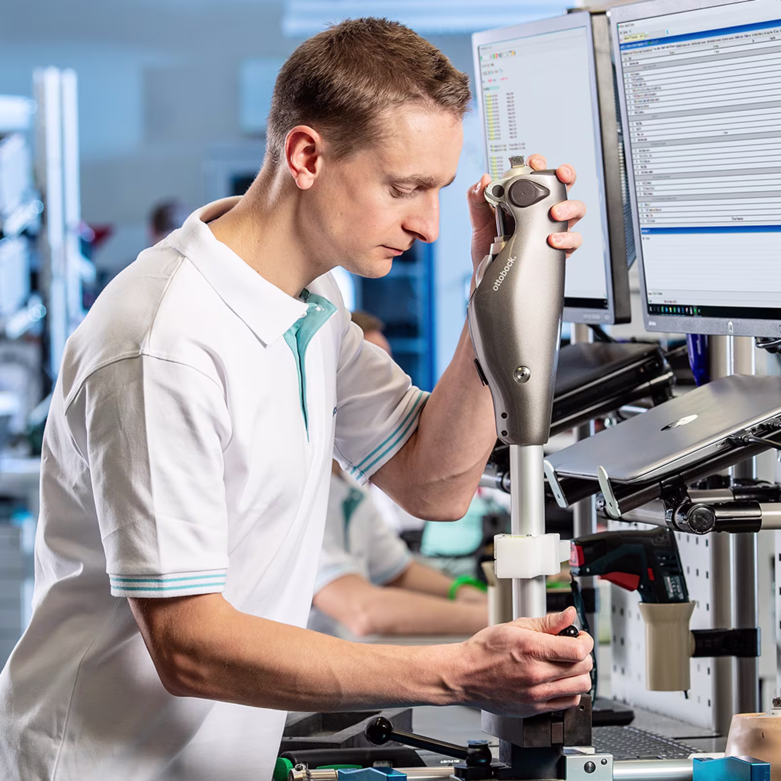 Ottobock technician using handheld device to inspect components in digital lab environment.