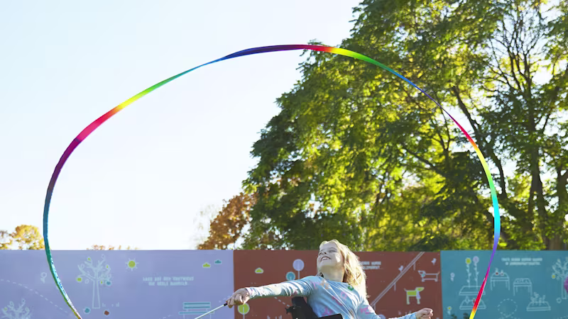 Genç bir kız, Nomine, kidevo tekerlekli sandalyesinin üzerinde renkli bir kurdeleyi döndürüyor. Jant kapakları mor ve mavi girdap desenine sahip.