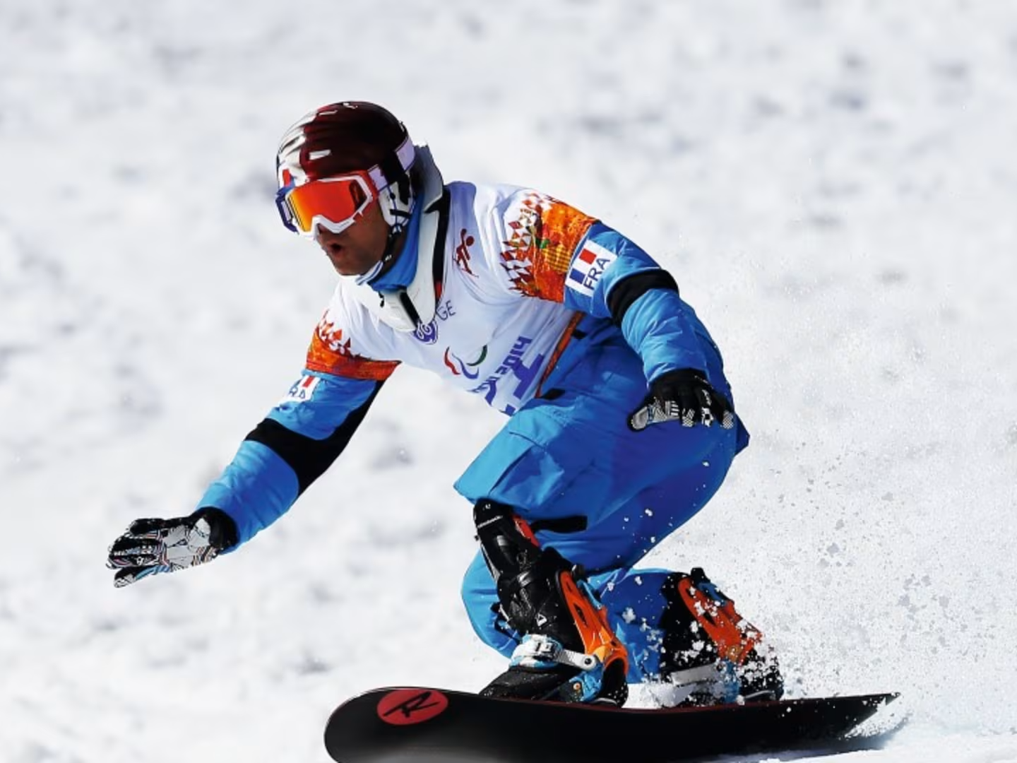 Adaptive snowboarder with a lower limb prosthesis riding on snow during a competitive winter sports event