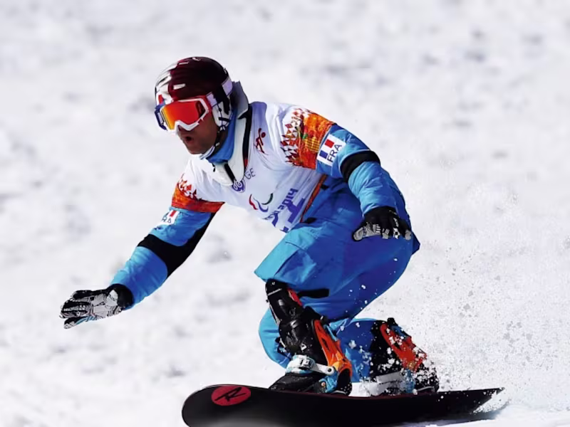 Adaptive snowboarder with a lower limb prosthesis riding on snow during a competitive winter sports event