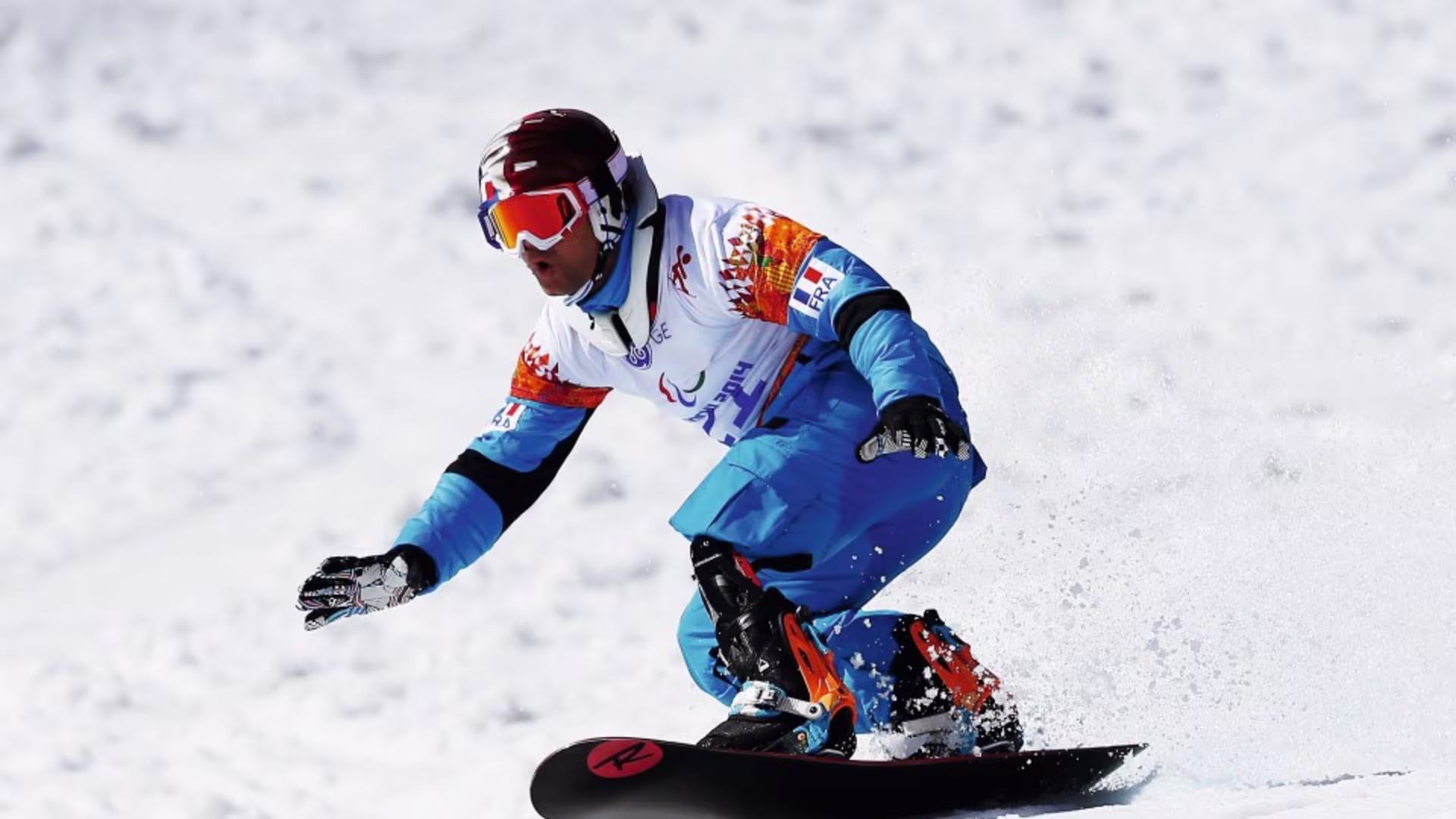 Adaptive snowboarder with a lower limb prosthesis riding on snow during a competitive winter sports event