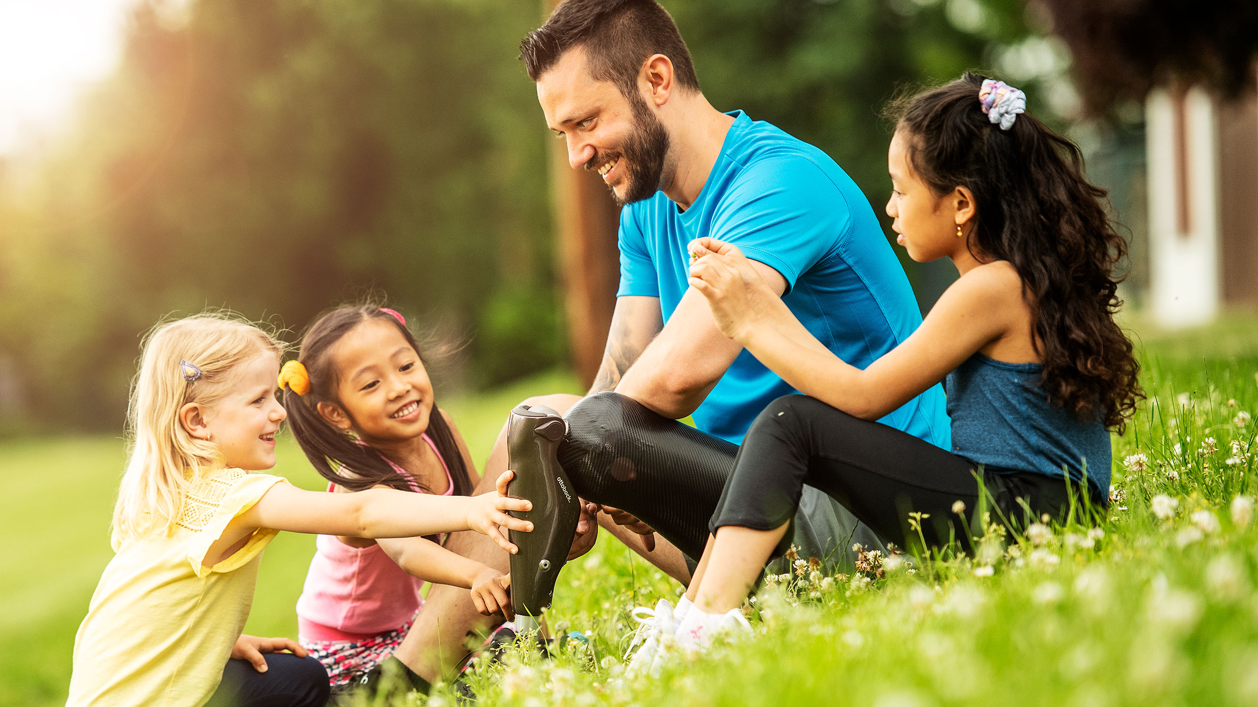 Georg si rilassa sull'erba con tre bambini e il suo C-Leg 4