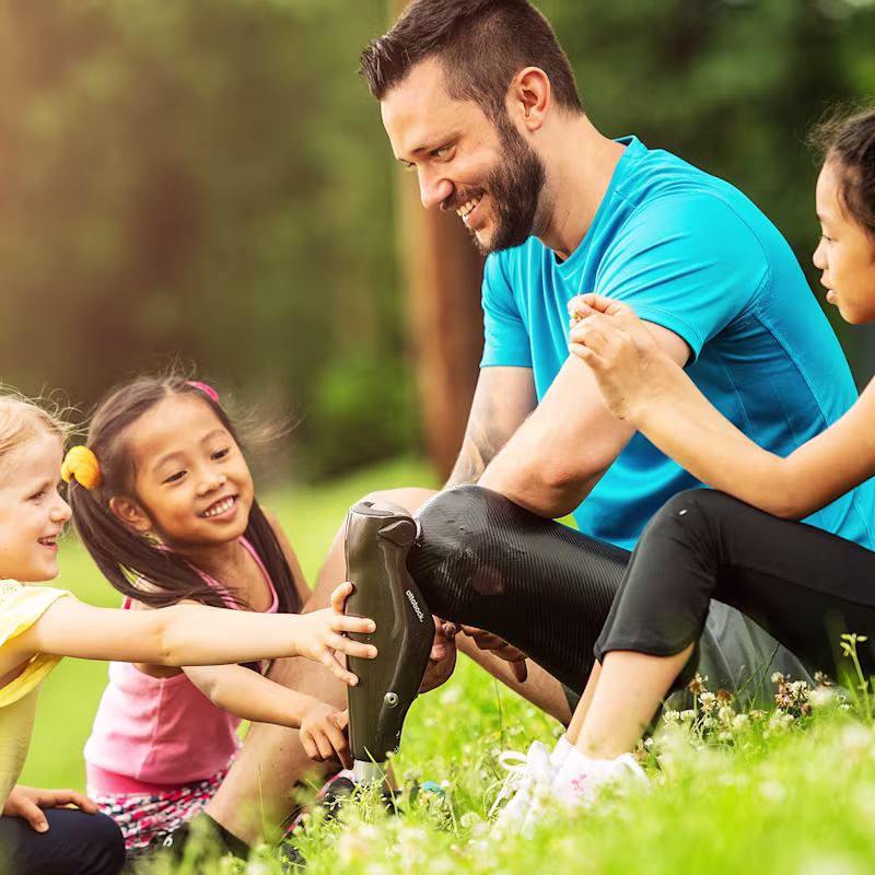 Georg relaxes in the grass with three children in his C-Leg 4