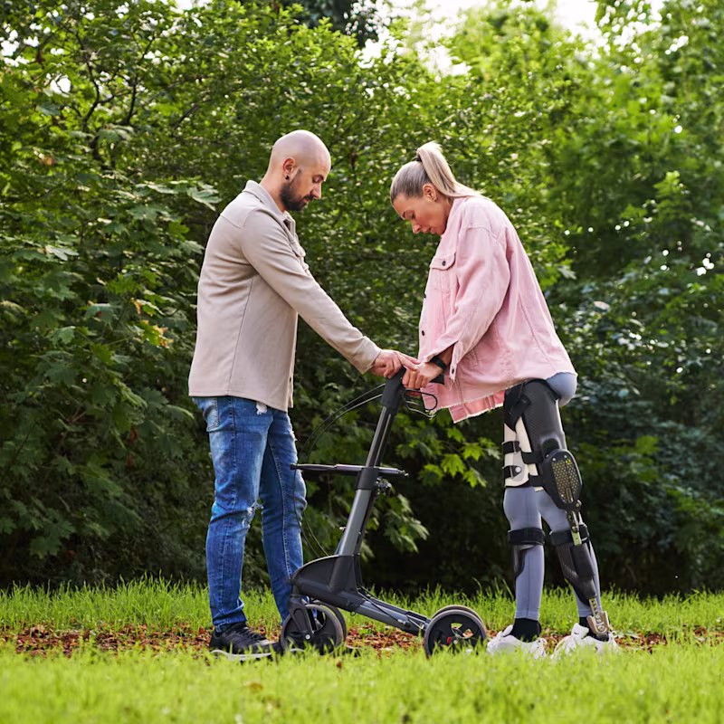 Ein Patient, der C-Brace verwendet, läuft in der Natur mit der Hilfe eines Mannes