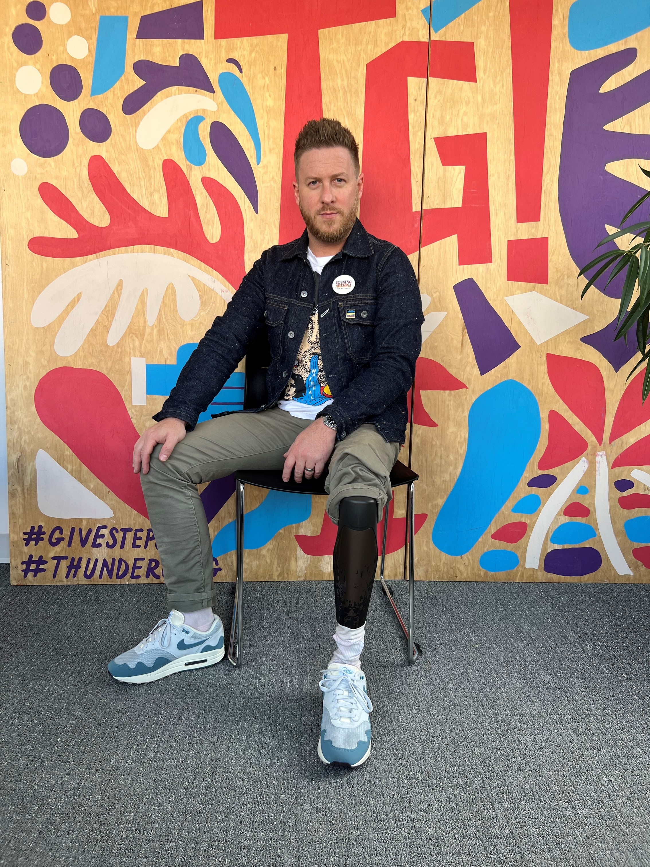 Billy Brimblecom poses in a bionic leg in front of a colorful mural