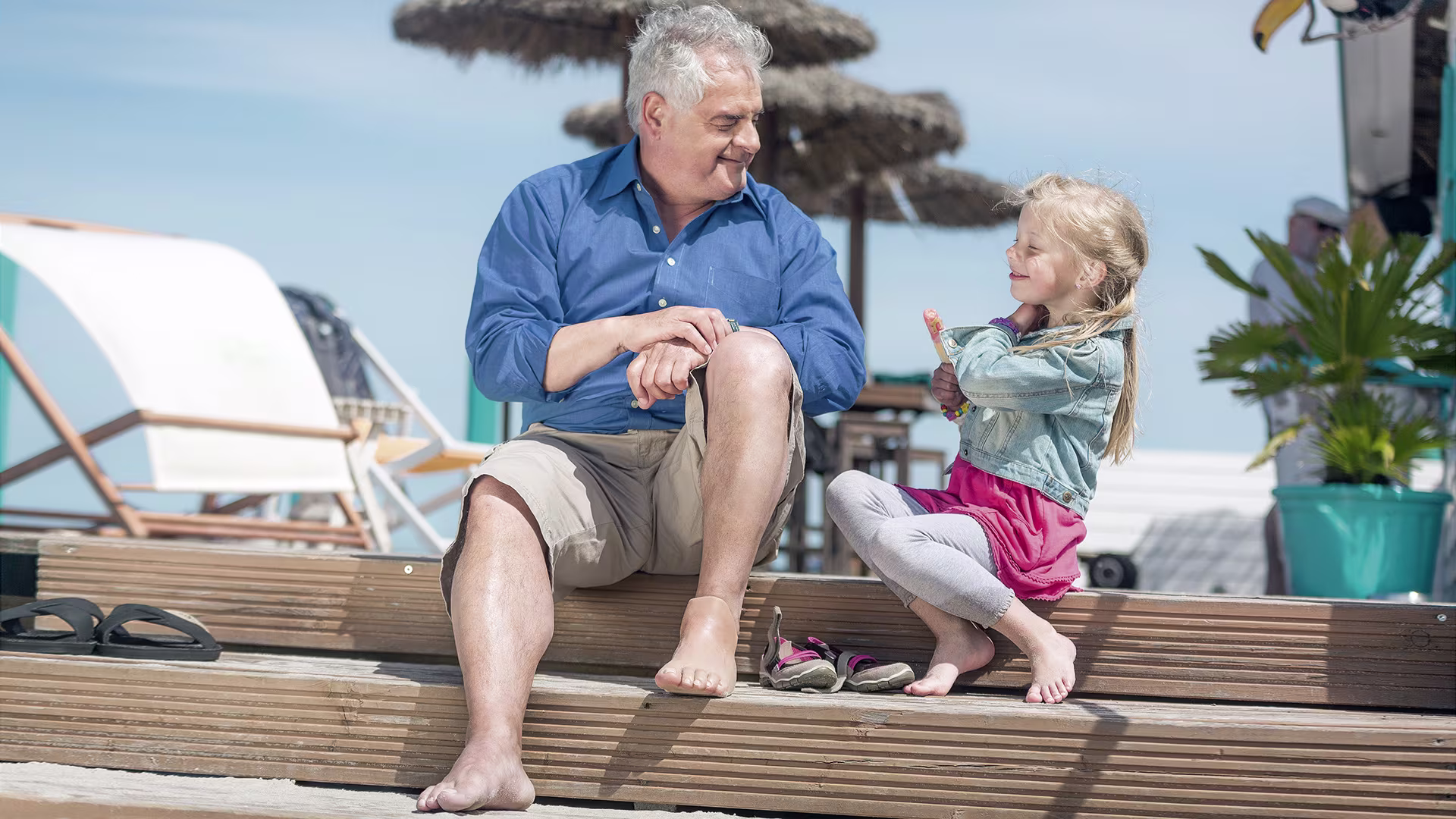 A grandfather with a foot prosthesis enjoys the sunny outdoors with his granddaughter