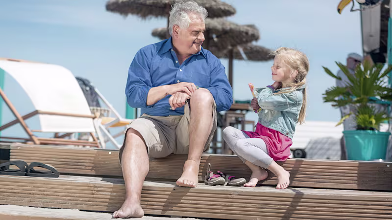 A grandfather with a foot prosthesis enjoys the sunny outdoors with his granddaughter
