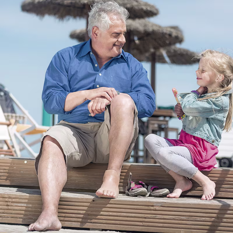 A grandfather with a foot prosthesis enjoys the sunny outdoors with his granddaughter