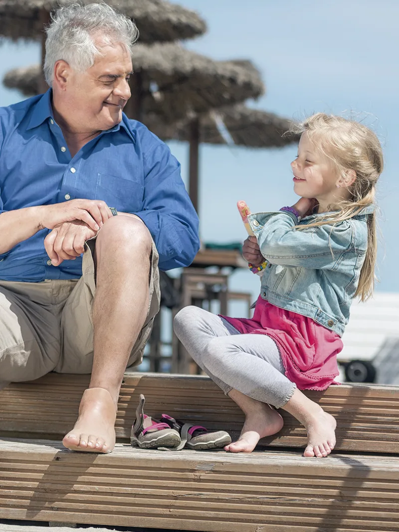 A grandfather with a foot prosthesis enjoys the sunny outdoors with his granddaughter 