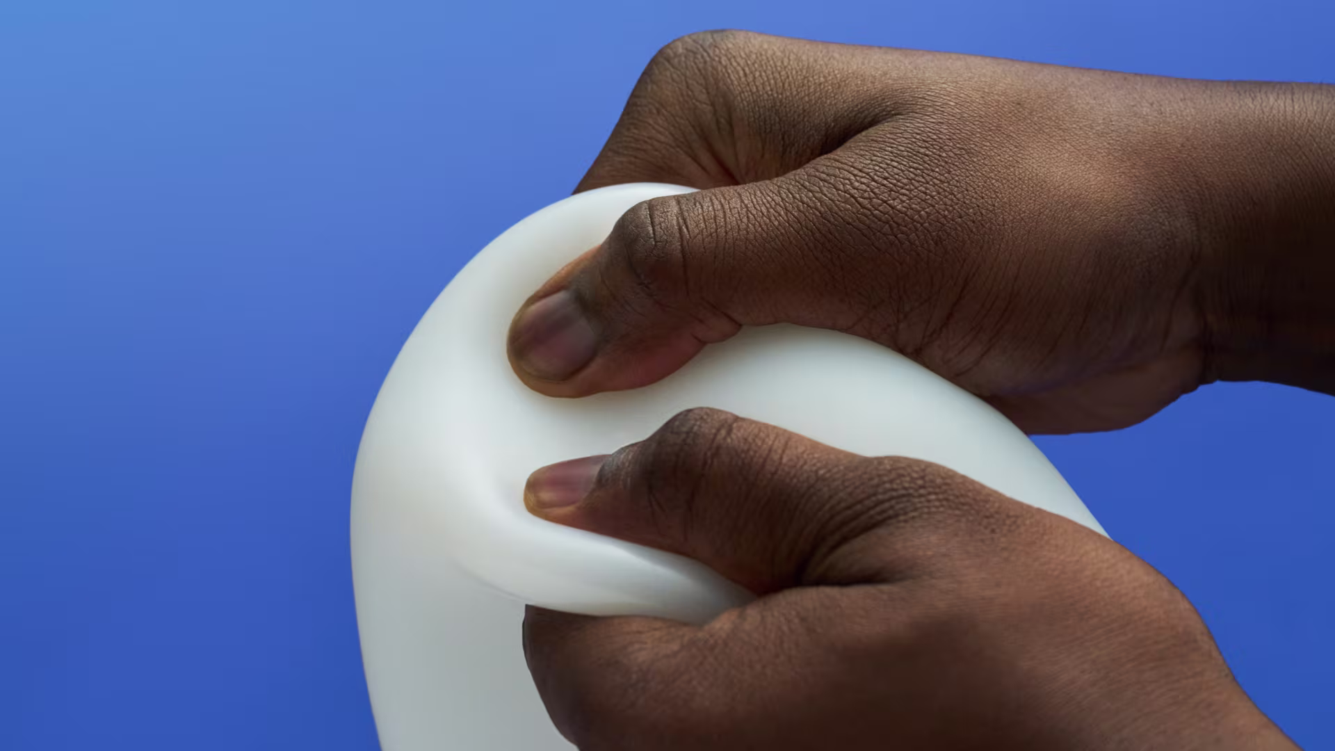 A close up to a person squeezing an Ottobock liner with their hands in front of blue background