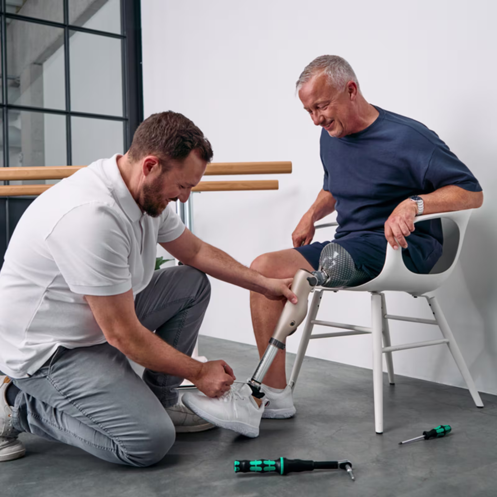 An orthopaedic technician adjusts a microprocessor‑controlled prosthesis on a seated patient.