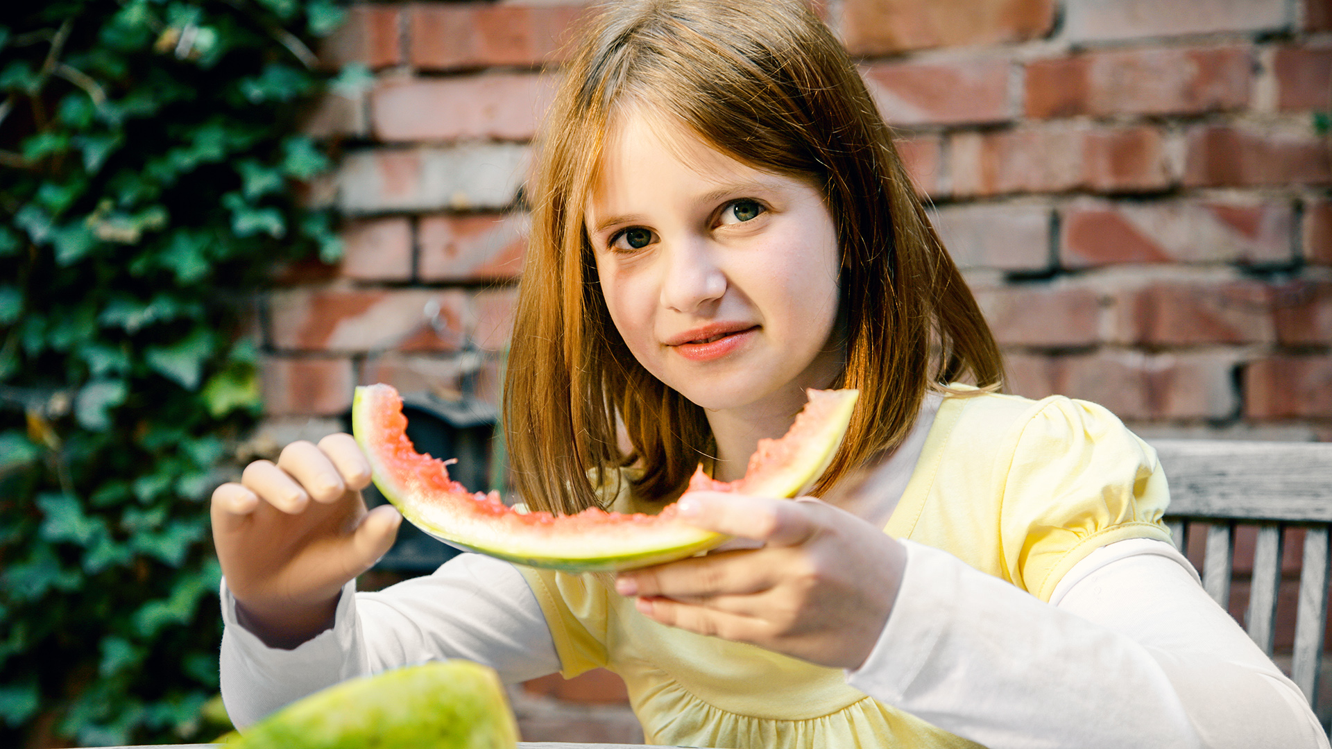 Child with Ottobock hand prosthesis eating a slice of watermelon.