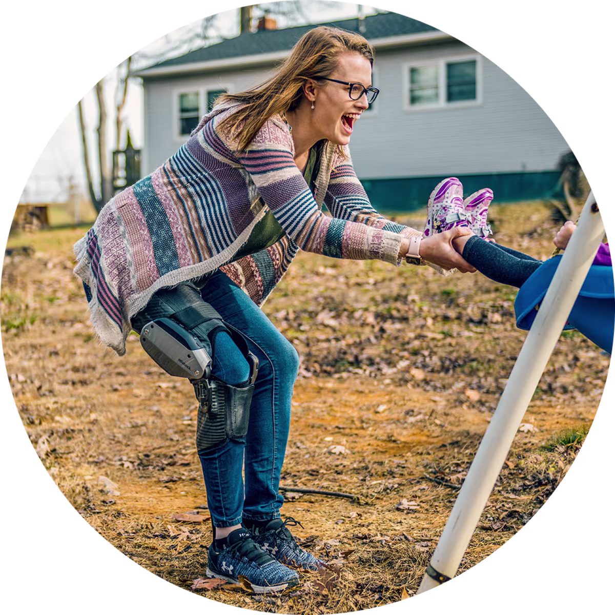 Eine Anwenderin spielt mit ihrem Kind auf dem Spielplatz und unterstützt das Kind beim Schaukeln, dabei trägt Sie ein C-Brace von Ottobock.