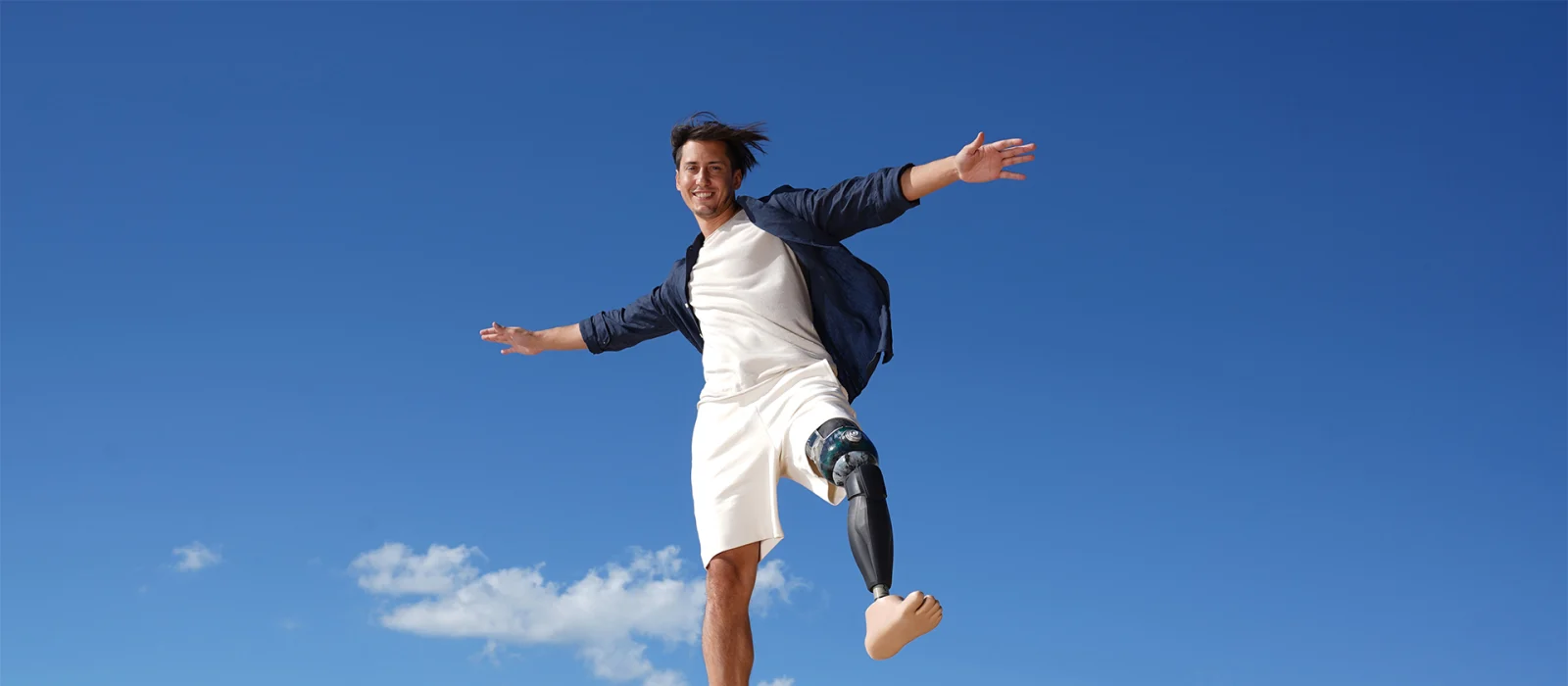 A male user stands smiling on a rock with his Ottobock Evanto prosthetic foot.