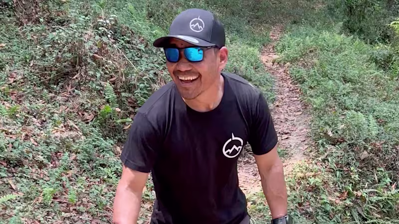 Male bilateral amputee Hari Budha Magar wearing Ottobock Genium X3 microprocessor knees and wanders a hiking trail smiling.