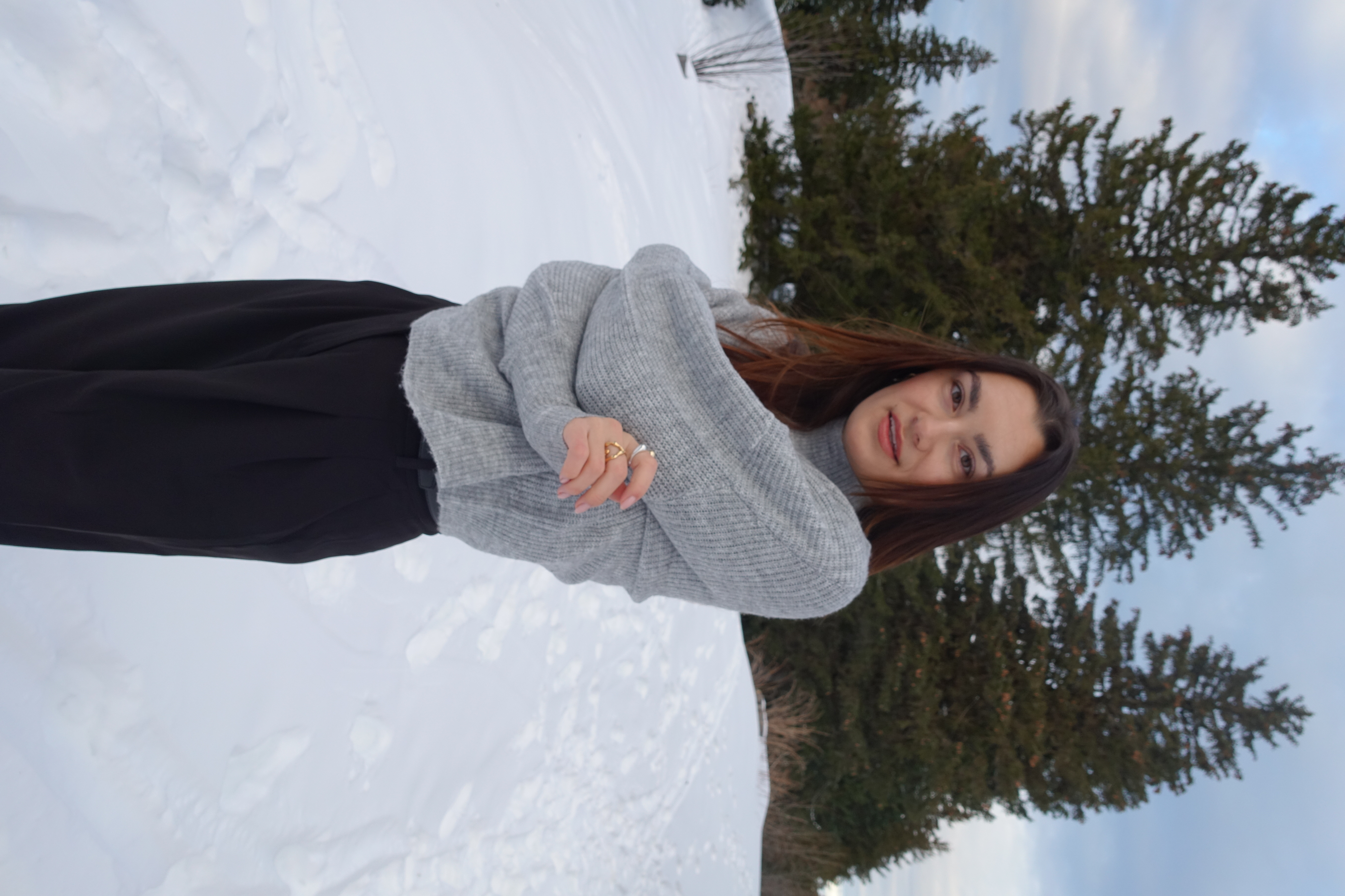 Ottobock beenprothesegebruiker Rebecca Brunner staat in de sneeuw, zichzelf te higgen. Ze draagt een grijze trui en een zwarte broek. 