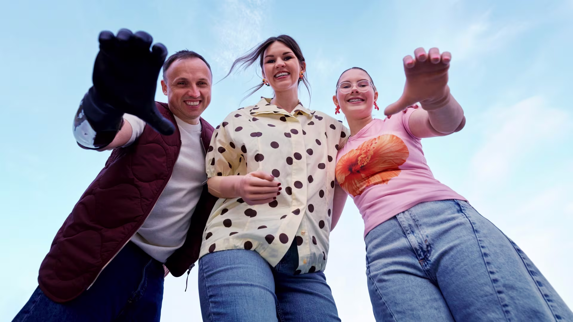 Three prosthetic users stand together, looking at the camera and holding their prosthetic arms forward.