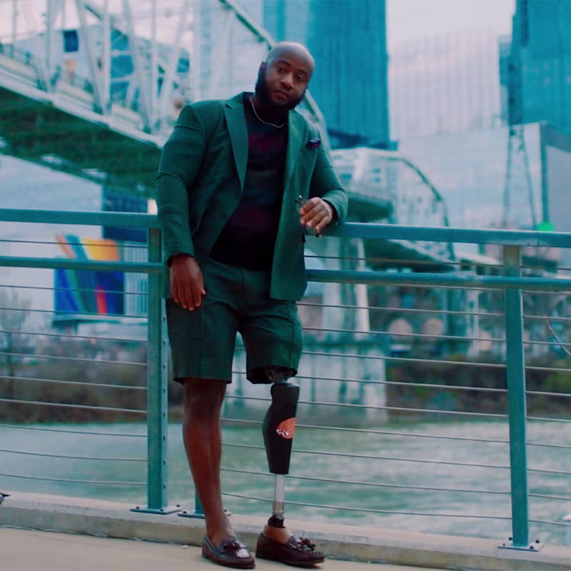 Con il suo C-Leg 4, Brandon si appoggia a una ringhiera che domina l'acqua e la città