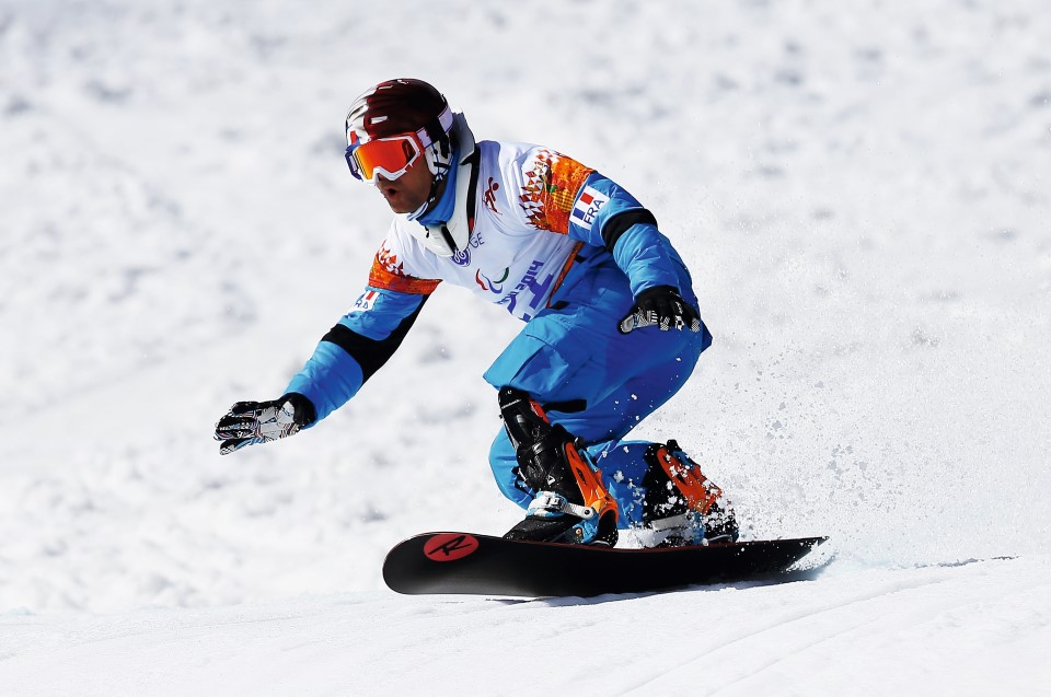 a paralympics athlete wearing uniform is snowboarding