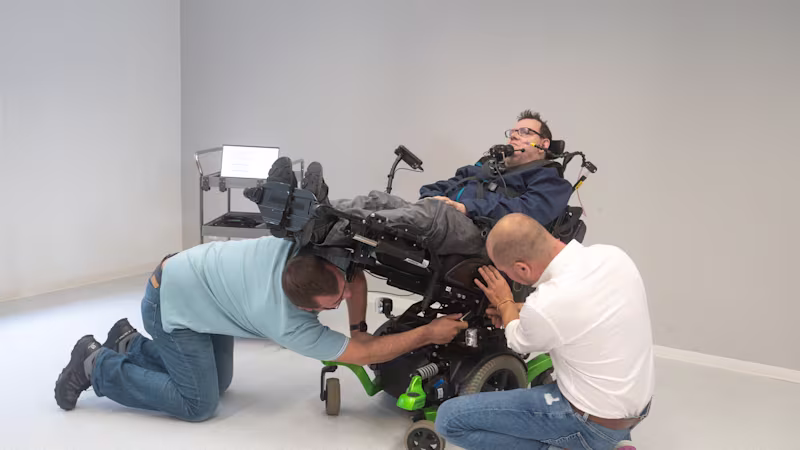 Ein Versorgungsspezialist und ein Sanitätshausmitarbeiter stellen die Breite zwischen den Armlehnen /sowie die Sitzbreite eines Elektrorollstuhls auf die Körpermaße des Anwenders ein