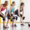 Three women working out with kettlebells. The woman in the forefront wears a prosthetic leg on her right side.