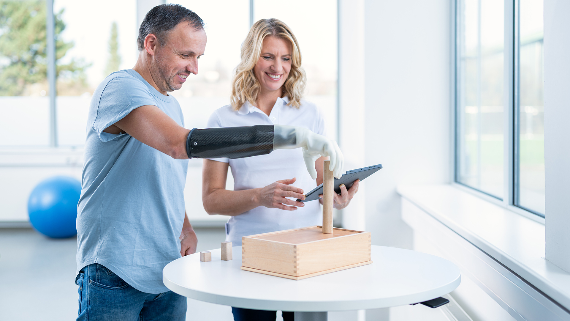 Eine Therapeutin trainiert mit einem amputierten Mann die Benutzung seiner michelangelo Prothesenhand von Ottobock.