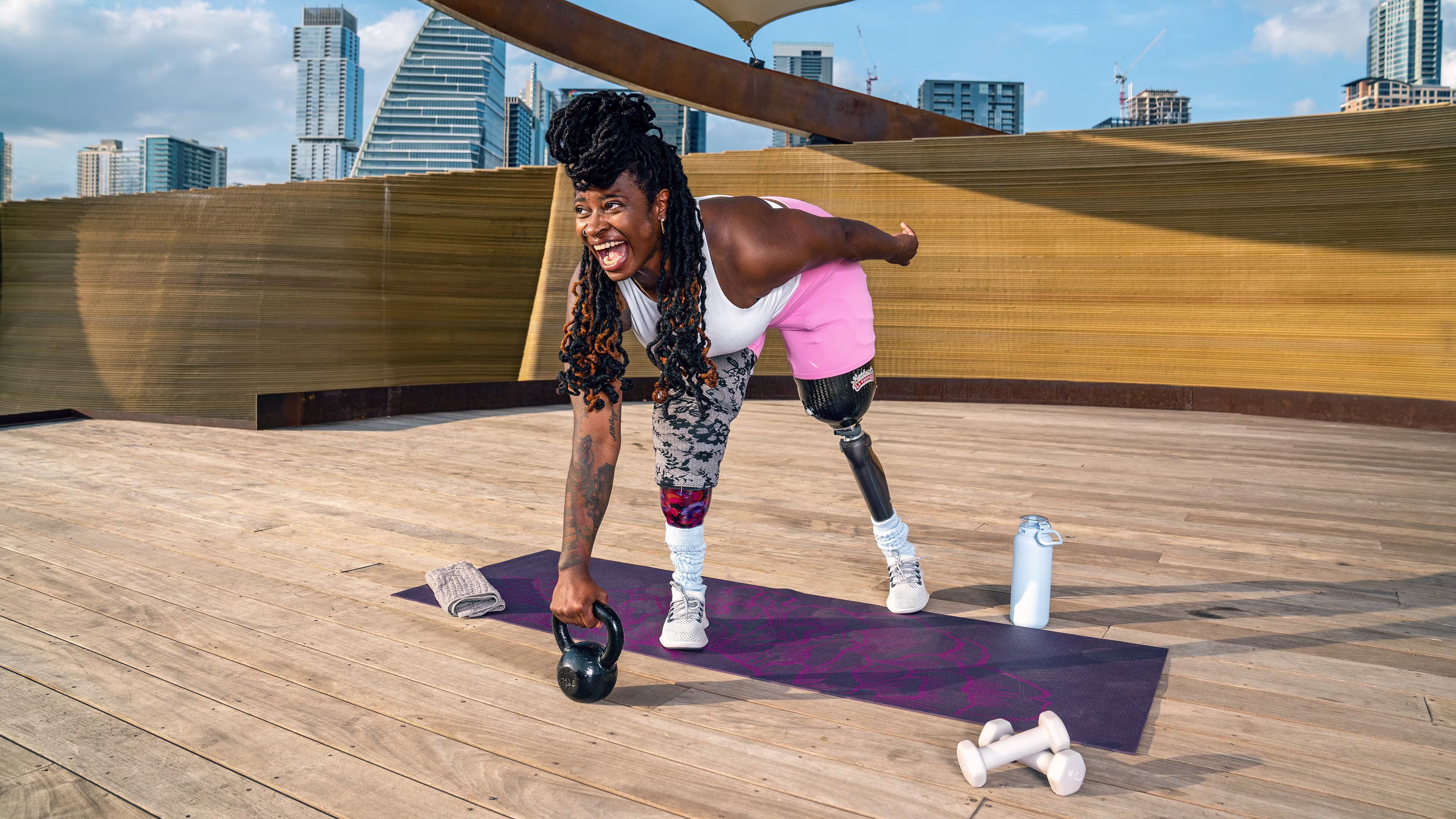 Athlete Shima, a prosthetic leg user, trains outdoors with a kettlebell, showing strength and adaptive fitness.