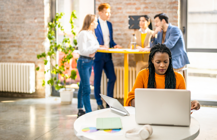 Vrouw op laptop met mensen op de achtergron - Eigenrisicodrager WGA