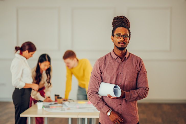 jonge man voor tafel met mensen in bespreking