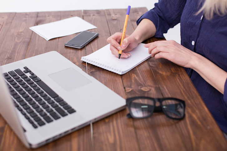 vrouw met notitieblok en computer 