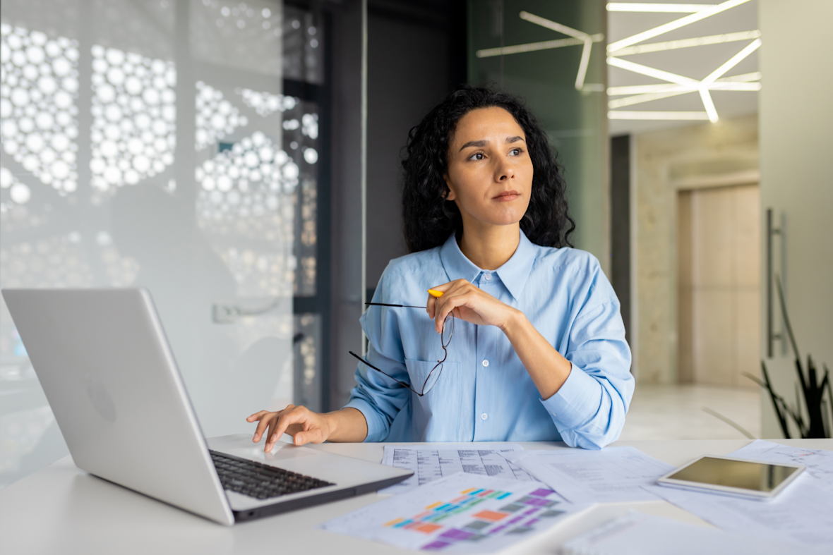 Serieuze vrouw aan het werk op kantoor, denkt na en kijkt weg