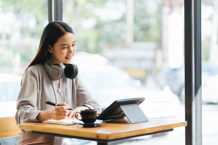 freelance jonge zakenvrouw met tablet en koptelefoon voert zelfstandig opdracht uit