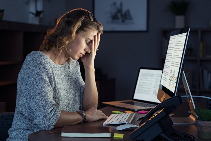 vrouw aan bureau met schermen stress