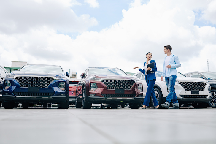 verkoper en koper lopen langs auto's